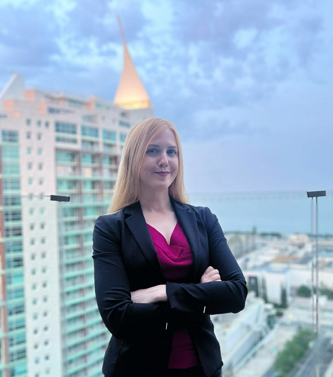 Photo of Marie Mejerwall in a suit with a tall modern building and a grey sky behind her